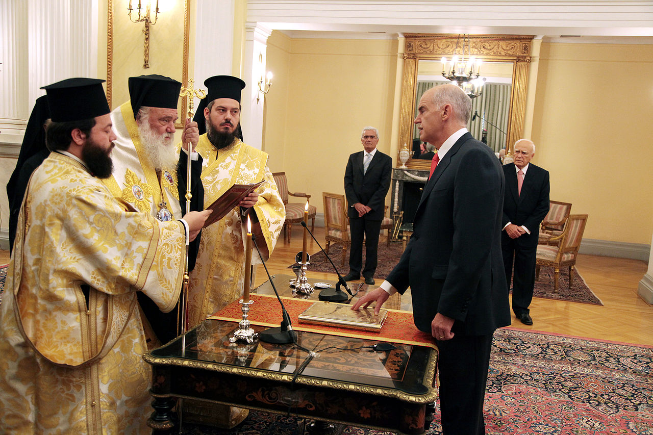 Assermentation de Papandréou en tant que Premier ministre de Grèce, devant l'archevêque d'Athènes Hieronimo II, au Palais présidentiel à Athènes, 6 ​​Octobre 2009. Source : ΠΑΣΟΚ