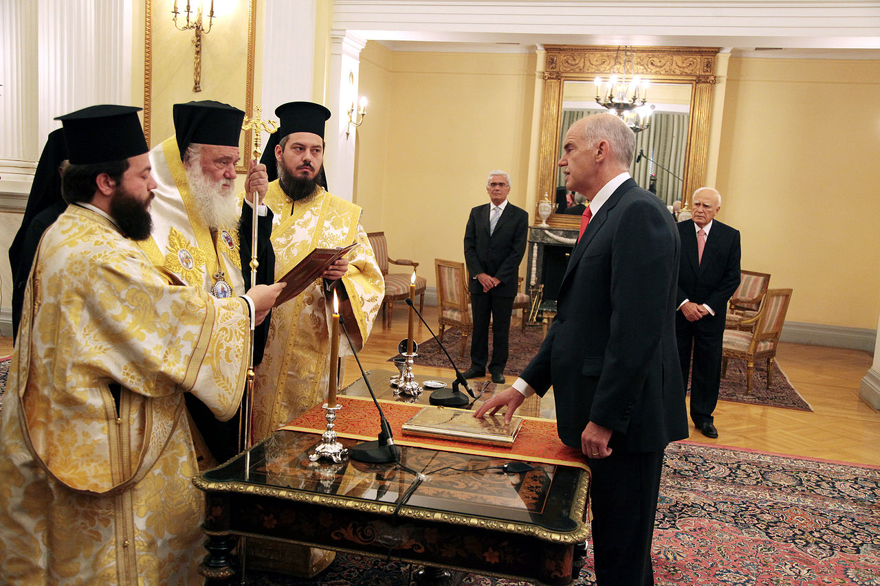 Assermentation de Papandréou en tant que Premier ministre de Grèce, devant l'archevêque d'Athènes Hieronimo II, au Palais présidentiel à Athènes, 6 ​​Octobre 2009. Source : ΠΑΣΟΚ